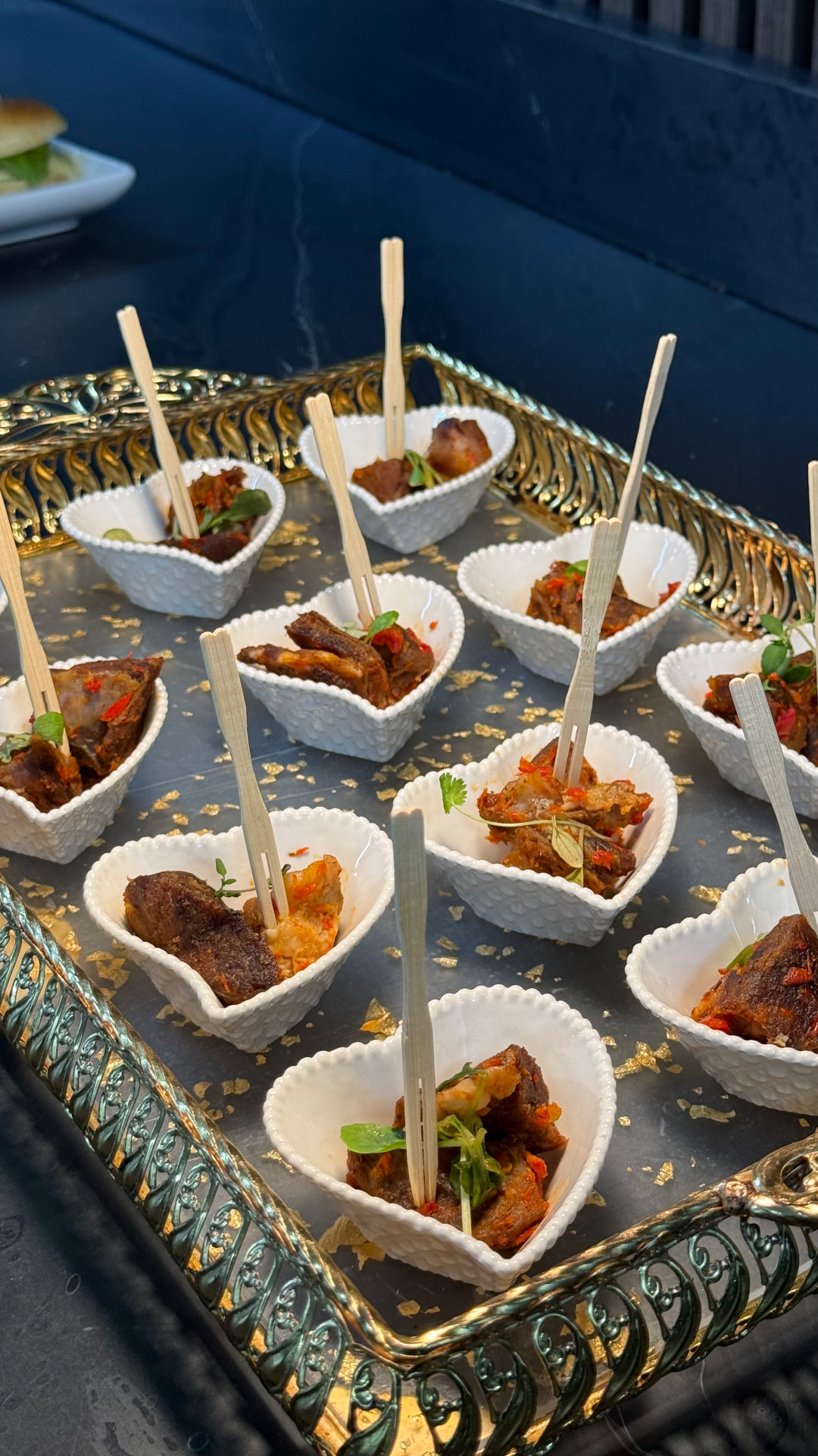 Peppered canapé bites in individual white bowls on an ornate gold tray