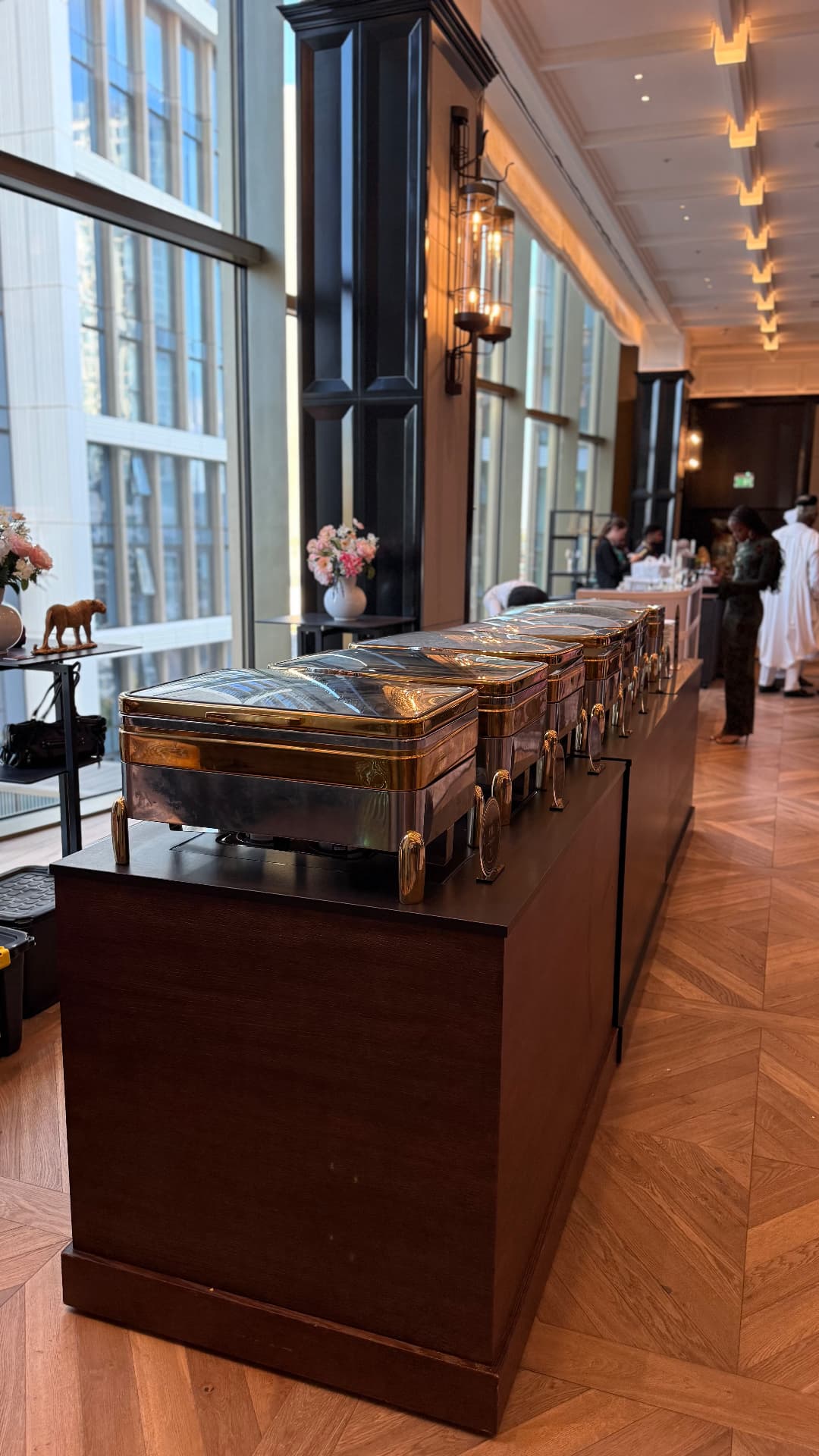 Gold chafing dishes arranged for buffet service in a bright elegant venue