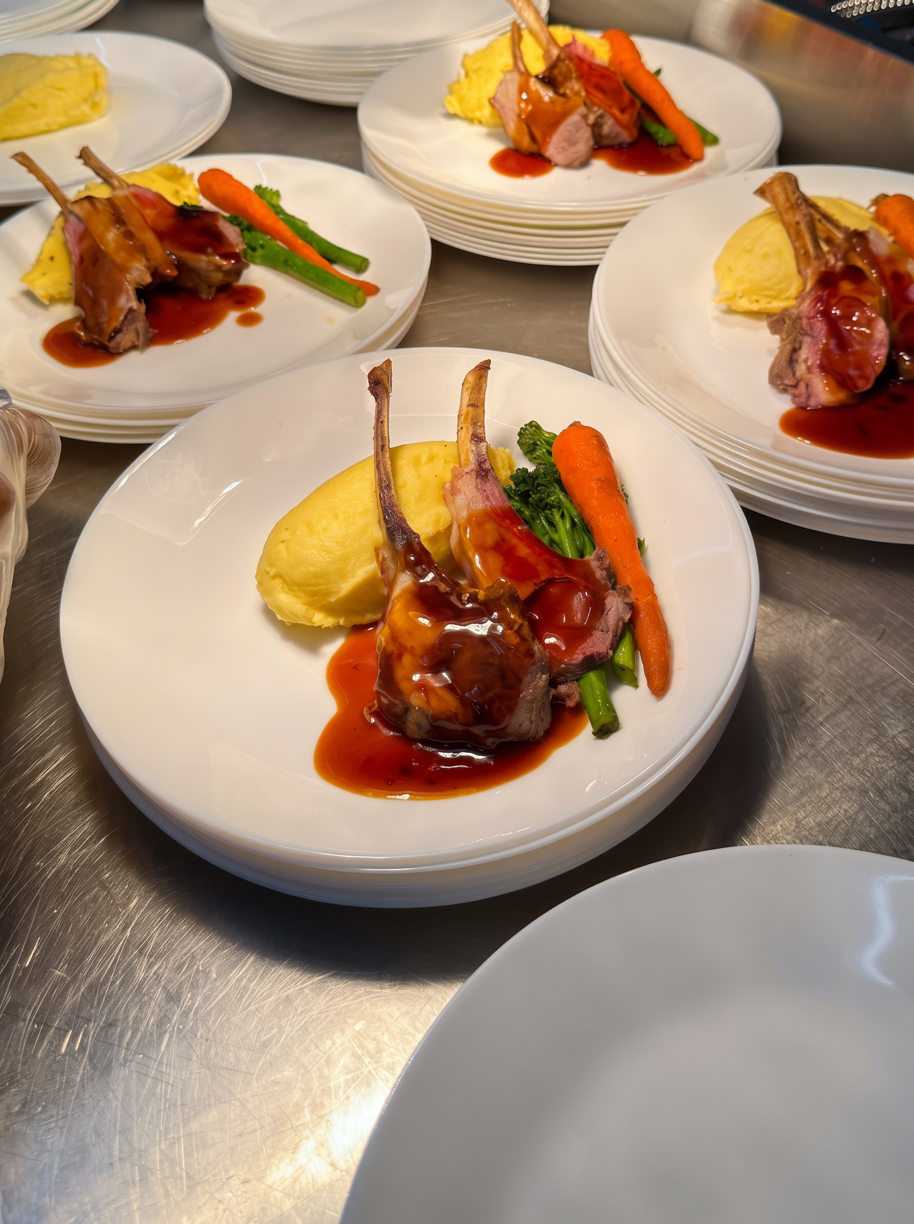 Lamb chops individually plated with vegetables and jus