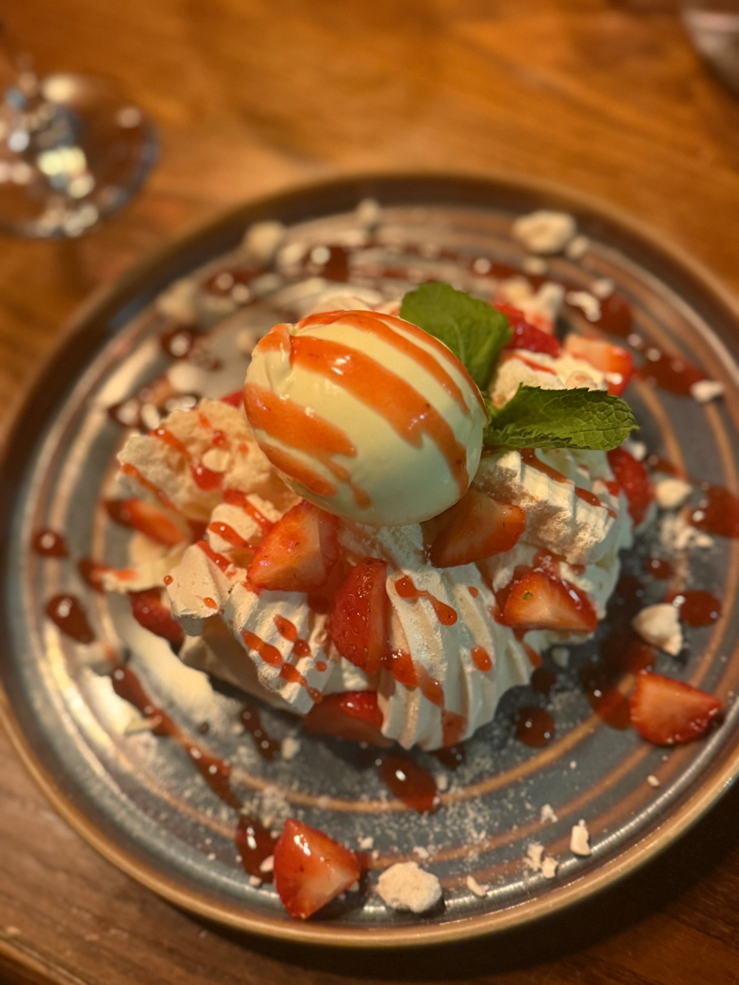 Strawberry pavlova dessert with cream, mint and sauce drizzle